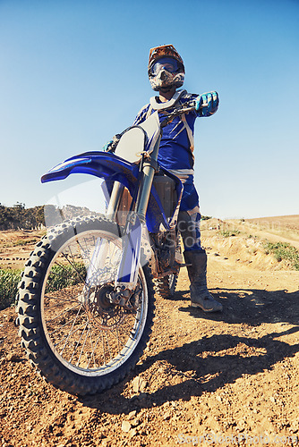 Image of Motorcycle, sports and danger with biker person outdoor, low angle with uniform for riding on dirt track. Speed, power and risk with motorbike, transportation and adventure for adrenaline and travel