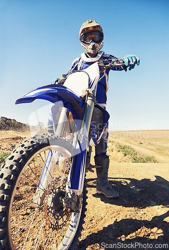 Image of Motorbike, sports and danger with biker person outdoor, low angle with uniform for riding on dirt track. Speed, power and risk with motorcycle, transportation and adventure for adrenaline and travel