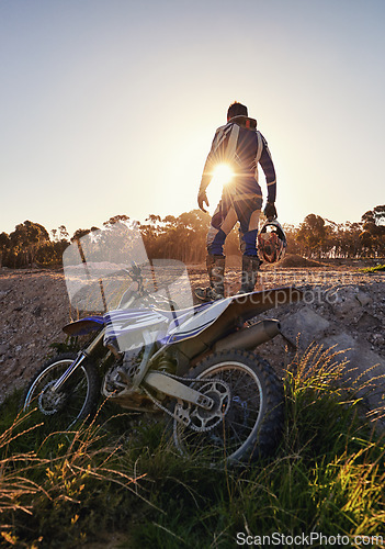 Image of Bike, off road sports and man with helmet on track at sunset for competition, race or training. Challenge, fitness and motorbike with person in sportswear gear outdoor for action or power from back