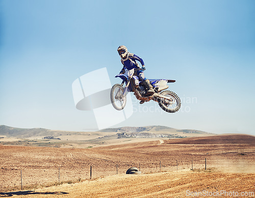 Image of Person, jump and dirt bike of professional motorcyclist in the air for trick, stunt or race on outdoor track. Expert rider on motorbike or scrambler in dunes or extreme sport with blue sky mockup