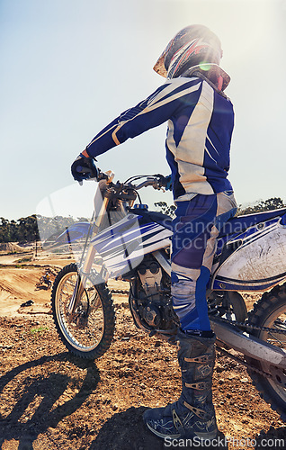 Image of Motorcycle, extreme sports and danger with biker person outdoor, sunshine with uniform for riding on dirt track. Speed, power and risk with motorbike, transportation and adventure for adrenaline