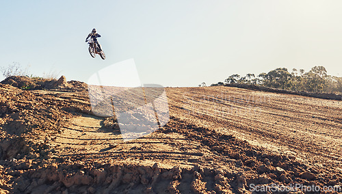 Image of Person, jump and dirt track of professional motorcyclist in the air for trick, stunt or race on outdoor terrain. Expert rider on motorbike or scrambler for extreme sports with blue sky background