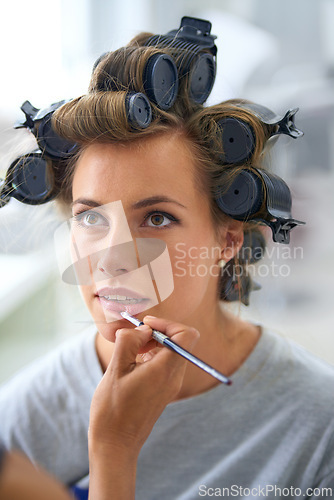 Image of Woman, apply lipstick and beauty or curlers, grooming and rollers for hairstyle by makeup artist. Female person, mouth and hair treatment for volume, skincare and makeover for behind the scenes