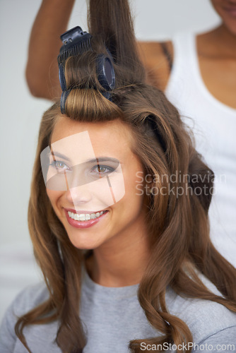 Image of Woman, face and happy with hair curlers for beauty, haircare and hairstyle with makeup or cosmetics at hairdresser. Person, smile and roller set for grooming, curling and getting ready with skincare