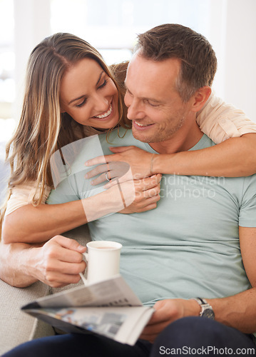 Image of Happy couple, care and newspaper with coffee in home and bonding together with love in marriage. Man, woman and hug by cappuccino for reading headlines, sofa and romantic indoor to relax on weekend