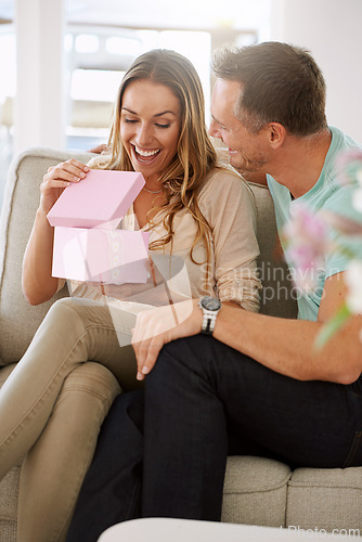 Image of Happy woman, surprise and open gift of man in lounge, excited and couple to celebrate valentines day in home. Husband, love and present for wife with kindness, gratitude and wow together on weekend