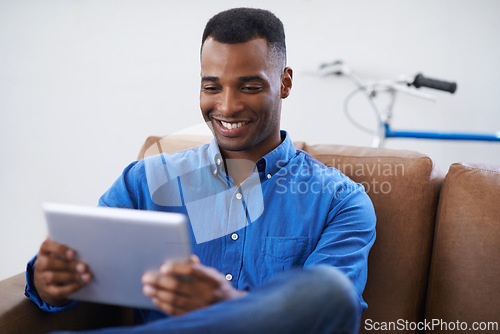 Image of Man, tablet and smile for social media at home, online and internet for website or blog. Black male person, relax and streaming entertainment on armchair, video call and app for shopping on weekend