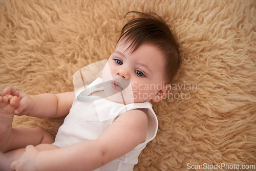 Image of Top view, carpet and adorable toddler in home, relax and happy on floor of nursery in room for resting. Child, playing and face of infant after nap in house for kid, comfortable and cute baby