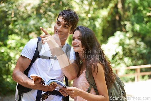 Image of Couple, map and point for adventure in woods with smile for thinking, holiday or hiking on path. Man, woman or guide for trekking, direction or search in rainforest with book for location in Colombia