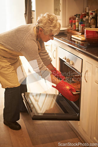 Image of Senior woman, oven and cooking pie at home in kitchen for food, nutrition and dessert. Female person, elderly lady or retired baking pastry dish on tray, pan or stove for eating, dining and enjoyment