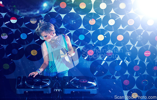 Image of Woman dj, headphones and vinyl records in night club for party with turntable, lights and lens flare. Gen z female person, retro or mixing decks at event with energy, techno and music in Berlin disco