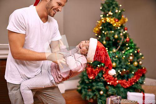 Image of Father, son and laughing with bonding on christmas for celebration, play and love in the morning with santa hats. Family, man and child with smile, relax and enjoying holiday season in lounge of home