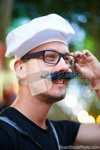 Image of Man, fake moustache and smile at carnival with costume for entertainment, celebration and party in France. Outdoor event, festival and fun for summer holiday to relax, music and enjoy vacation.