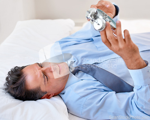 Image of Businessman, alarm clock and upset to wake up for work and schedule in the bed at home. Mature male person, clock and frustrated with watch for appointment and sleep or fatigue while lying in bedroom