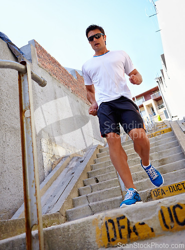 Image of Man, stairs and earphones for running outdoors, sports and athlete for performance training in city. Male person, full body and sunglasses for workout in town, cardio and listen to music for exercise