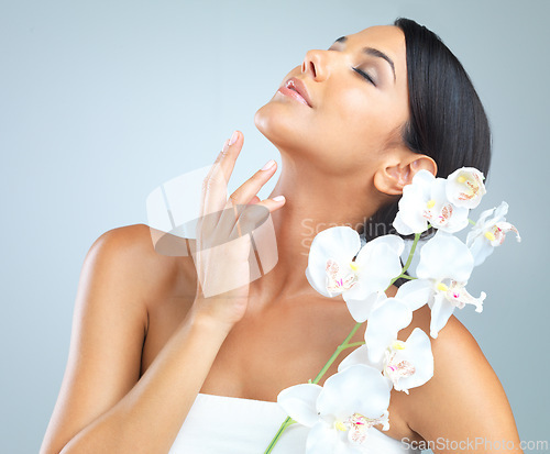 Image of Flowers, skincare and woman with beauty, dermatology and person on a grey studio background. Model, luxury or girl with aesthetic or natural with facial or shine with glow and cosmetics with wellness