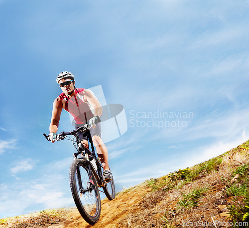 Image of Nature, fitness and man athlete with bicycle in park for marathon, race or competition training. Blue sky, sports and male cyclist riding bike for cardio workout or exercise in outdoor forest.