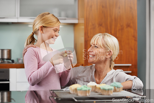 Image of Happy, mom and child with cupcake in kitchen and learning about baking together in home to relax. Family, bonding and kid smile with mother, excited for eating cake, sweets or enjoy food in house