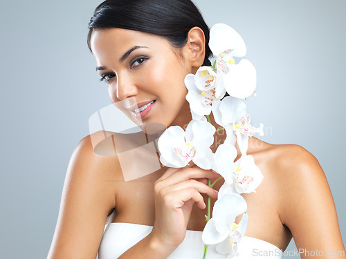 Image of Portrait, woman and beauty with flower in smile on studio, grey background and satisfied with makeup. Female person, soft and natural for smooth skin with eco friendly, sustainable and happiness.