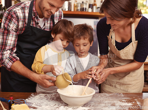 Image of Family, smile and kids baking in kitchen, learning or happy boys bonding together with parents in home. Father, mother or children cooking with flour, food and brothers pour milk in bowl at table