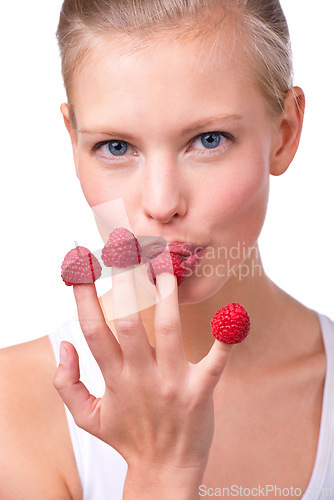 Image of Portrait, breakfast and raspberries on fingers of woman in studio isolated on white background for diet. Face, health and food on hand of young person eating fruit for weight loss, detox or nutrition