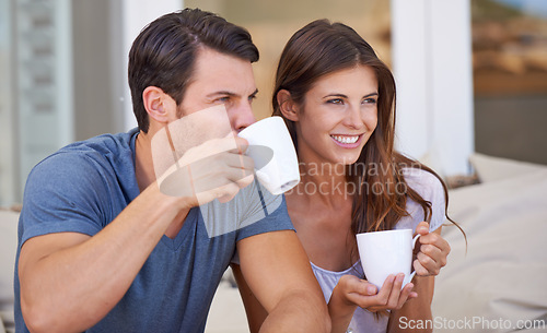 Image of Couple, morning and lounge with coffee in home for smile, thinking and relax on sofa with drink. Man, woman and happy together with latter, coco or tea cup with bonding, love and ideas on vacation