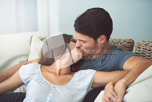 Image of Love, kissing and couple relaxing on sofa by patio cuddling and bonding for marriage at home. Happy, romance and young man and woman resting together on couch by outdoor porch of modern house.