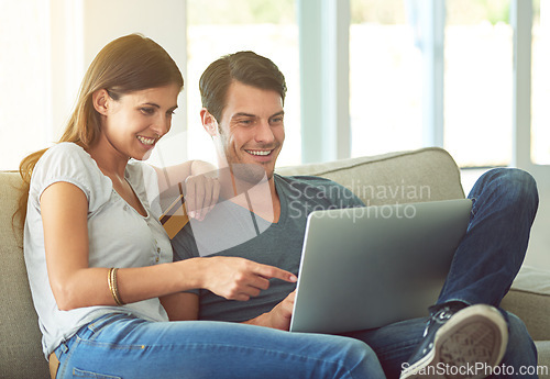 Image of Happy couple, pointing and laptop with credit card for ecommerce, payment or purchase on sofa at home. Man and woman with smile or debit on computer for choice or order in online shopping or banking