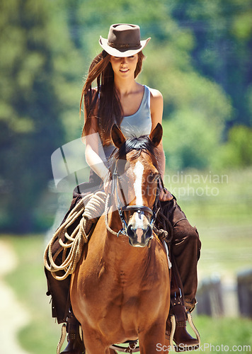 Image of Woman, cowgirl and horse riding in the countryside for journey, travel or outdoor adventure in nature. Female person or western rider with hat, saddle and animal stallion at ranch, farm or stable