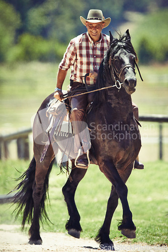 Image of Cowboy, smile and man riding horse with saddle on field in countryside for equestrian or training. Agriculture, summer and happy mature horseback rider on animal at ranch outdoor in rural Texas