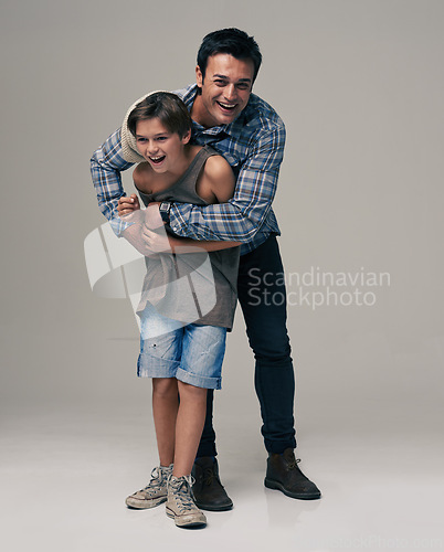 Image of Happy father, portrait and child laughing with hug for love, care or support in fashion on a gray studio background. Dad playing with son or kid in happiness for parenting or bonding on mockup space