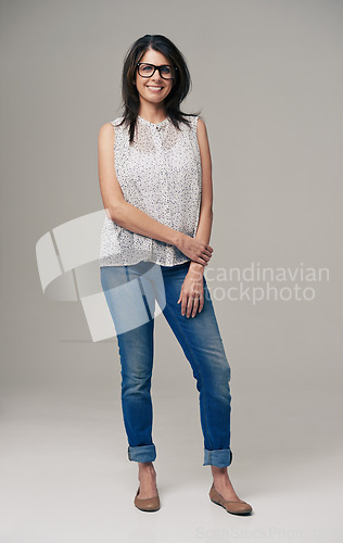 Image of Happy woman, portrait and fashion with glasses, denim jeans or style on a gray studio background. Female person, brunette or adult with casual clothing or stylish outfit in confidence on mockup space