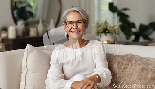 Image of In her sunlit living room, the modern elderly woman exudes sophistication, wearing glasses, creating a chic and cozy atmosphere.