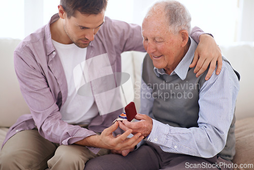 Image of Father, son and medal at home, smile and happy relationship in house. Family bonding, proud dad and child on sofa sitting together, elderly man and giving award at living room after retirement