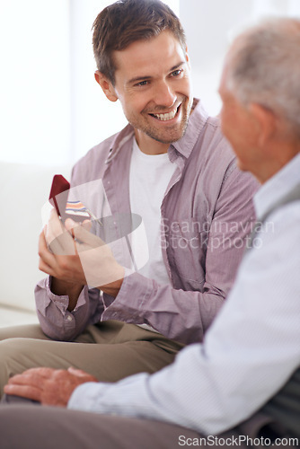 Image of Senior dad, son and medal for surprise present, support and congratulations with celebration and bonding at home. Men in living room, family with reward or award as gift for happiness and gratitude