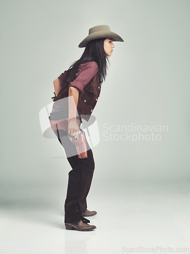 Image of Woman, cowgirl and weapon in studio, clothing for wild west gun, outfit and halloween costume with holster. Female person, cowboy hat and boots from Texas, white background and dress up like bandit