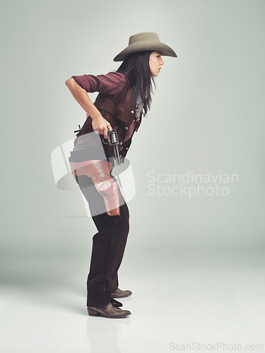 Image of Woman, cowgirl and outfit in studio, pistol holster and halloween costume for wild western boots. Female person, cowboy hat and clothes from Texas, white background and dress up with bandit gun