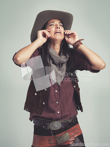 Image of Crying, cowgirl and unhappy with sad expression in studio with stress, tears and upset with sorrow. Female person, costume and hat for western fashion, isolated and emotional with grey background