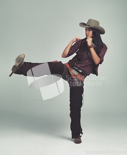Image of Cowgirl, kick and fight with fists in studio for western character, wild west outfit and hat for sheriff. Female person, costume and angry with aggression, rage and isolated with grey background