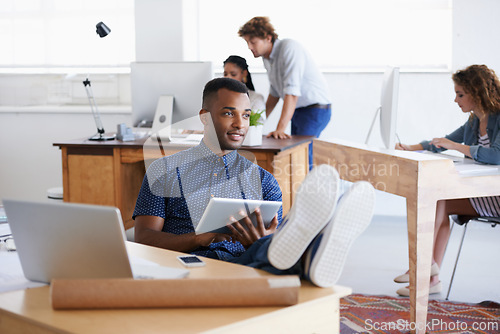 Image of Male, tablet and laptop in office with desk for thinking, research or business. African person and architect with technology, internet or web online for design, innovation and planning in Dublin.
