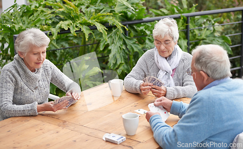 Image of Elderly people, card games and coffee at table with outdoor background for retirement and old age. Group, seniors or family with beverages and thinking for poker, relax and break together on patio