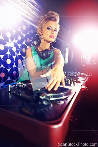 Image of Portrait, woman dj, and headphones with vinyl in night club with mixing decks and lens flare. Female person, turntable and hands for spinning, tracks and music with energy at disco in Berlin