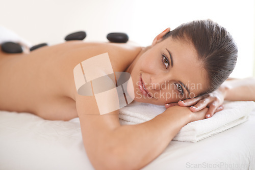 Image of Hot stone, massage and portrait of woman in spa to relax for skincare, beauty or pamper body for wellness at luxury salon.Therapy, rocks and face of happy person in treatment, health and resting