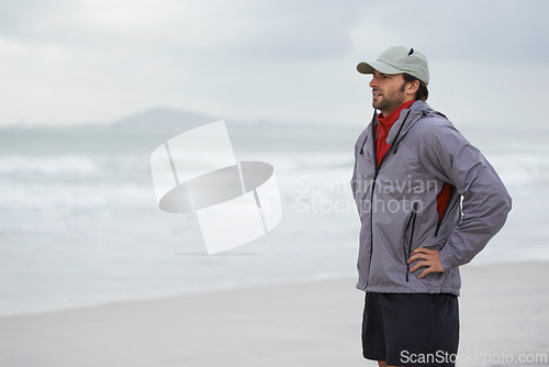 Image of Fitness, man and thinking break at a beach after training, running or winter morning cardio in nature. Workout, recovery and male runner at the sea for sports rest, breathing or body wellness routine