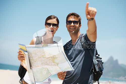 Image of Couple, map and search with pointing by beach, mountains and excited for giving direction on vacation. Woman, man and chart for location, landmark and travel for memory in holiday by ocean in Italy