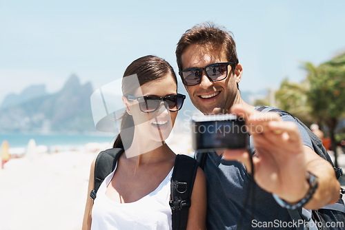 Image of Couple, beach and camera for selfie on holiday with smile, sunglasses and outdoor for memory in summer. People, man and woman with photography by ocean for journey, vacation and sunshine in Italy