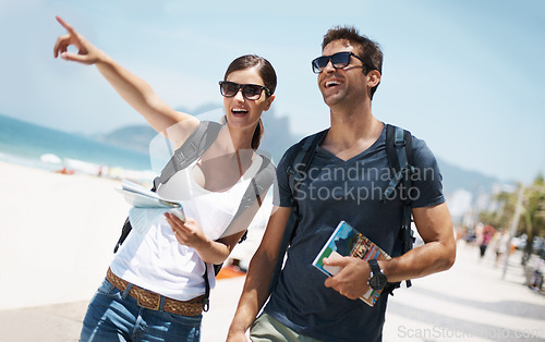 Image of Couple, holiday and pointing with map at beach as tourist in summer, trip and smile for adventure in Brazil. Directions, relationship and bonding on vacation in seaside for travel, break and happy