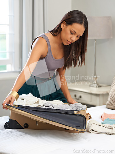 Image of Travel, clothes and woman packing luggage for vacation, holiday and planning in home. Bedroom, serious person and suitcase for trip preparation, journey or getting ready for tourism with bag on bed