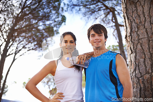 Image of Smile, couple and trees in nature for fitness, water and sports marathon break for running and exercise. Wellness, vitality and healthy lifestyle in summer, forest trail and cardio training together