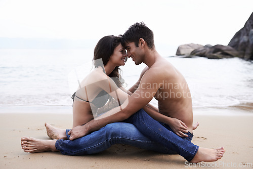 Image of Couple, embrace and sitting on beach with love in nature on holiday or vacation in summer. People, smile and moment to relax together on date or travel in Florida at sea or hug partner with gratitude